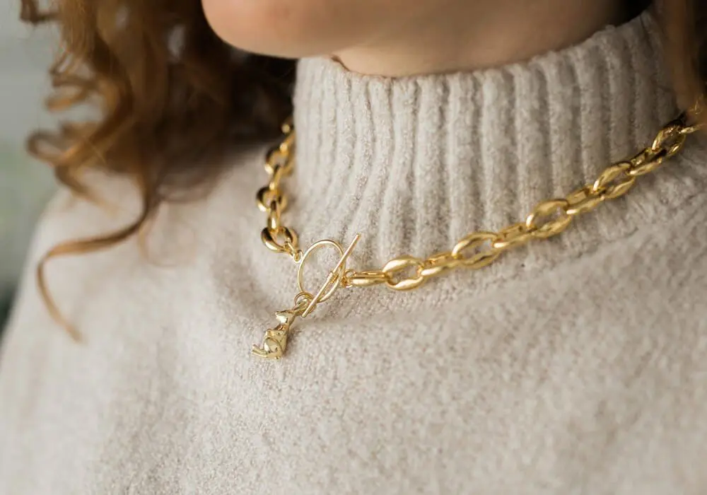 Gold chain necklace worn over a cream sweater