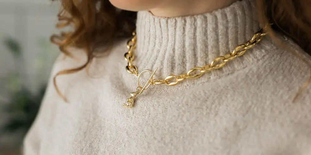 Woman in a cream sweater wearing a gold chain necklace