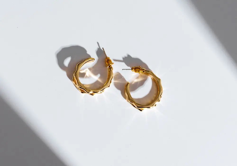 Gold hoop earrings on a white surface