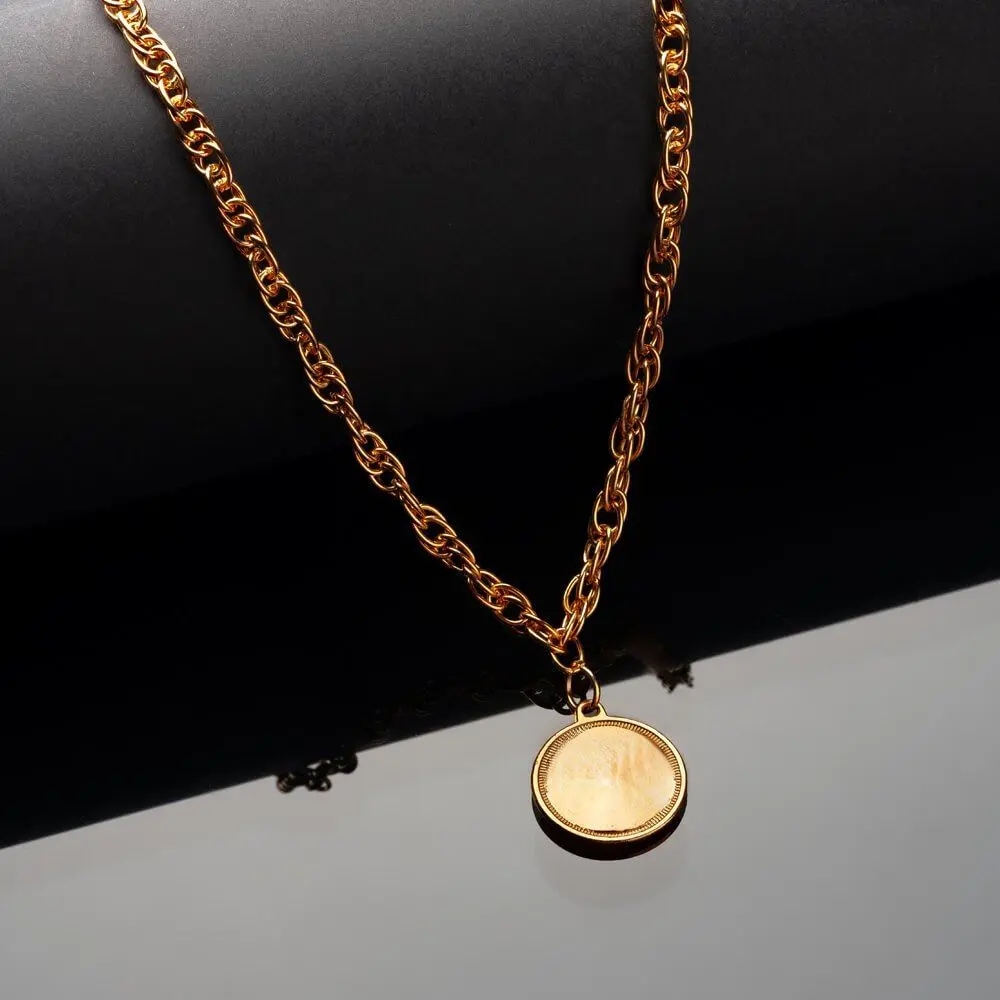 Gold chain necklace with a round pendant on a dark background