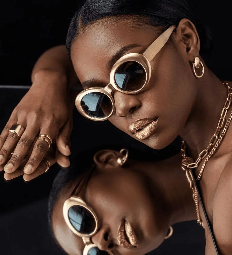 Woman in sunglasses wearing gold rings and a gold necklace