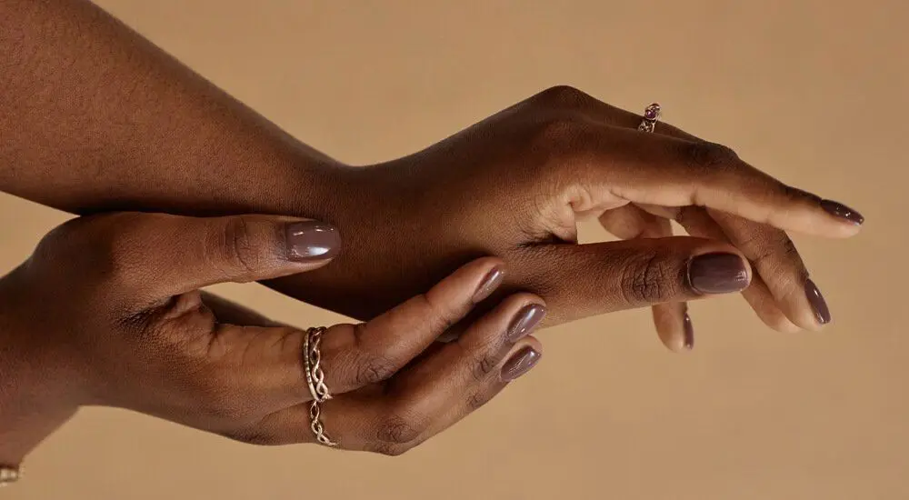 Hands wearing gold rings against a warm background
