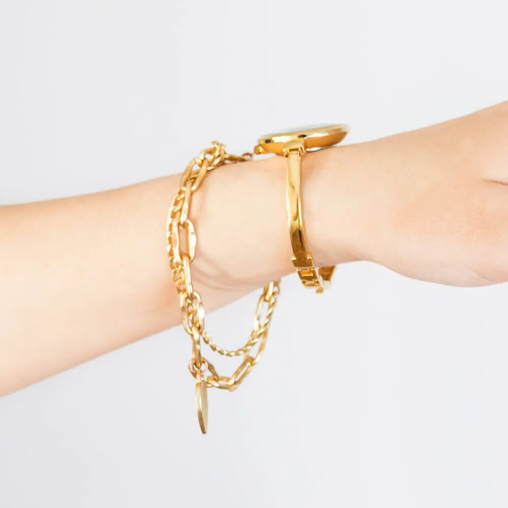 Layered gold bracelets on a wrist