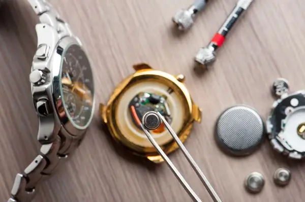 Hands replacing the battery inside a watch