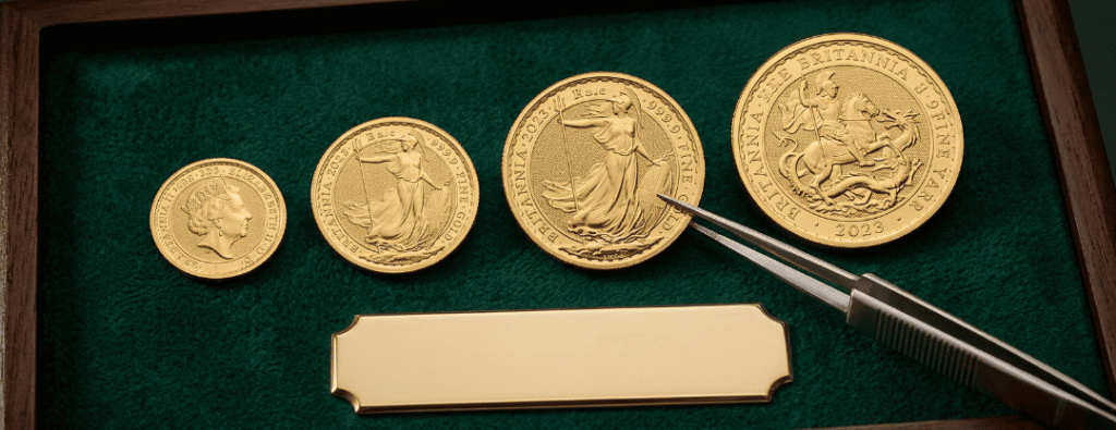 Close-up of gold Britannia coins showing both the iconic Britannia figure with trident and shield and the monarch's portrait, displayed on a dark professional background to highlight the 24ct gold luster and intricate design details.
