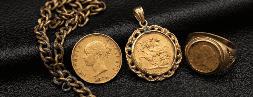 A collection of gold sovereign coins in various conditions, including a Victorian sovereign, a coin mounted in an ornate gold pendant, and a signet ring, displayed on a black leather surface to show acceptance of jewelry-mounted and circulated coins.
