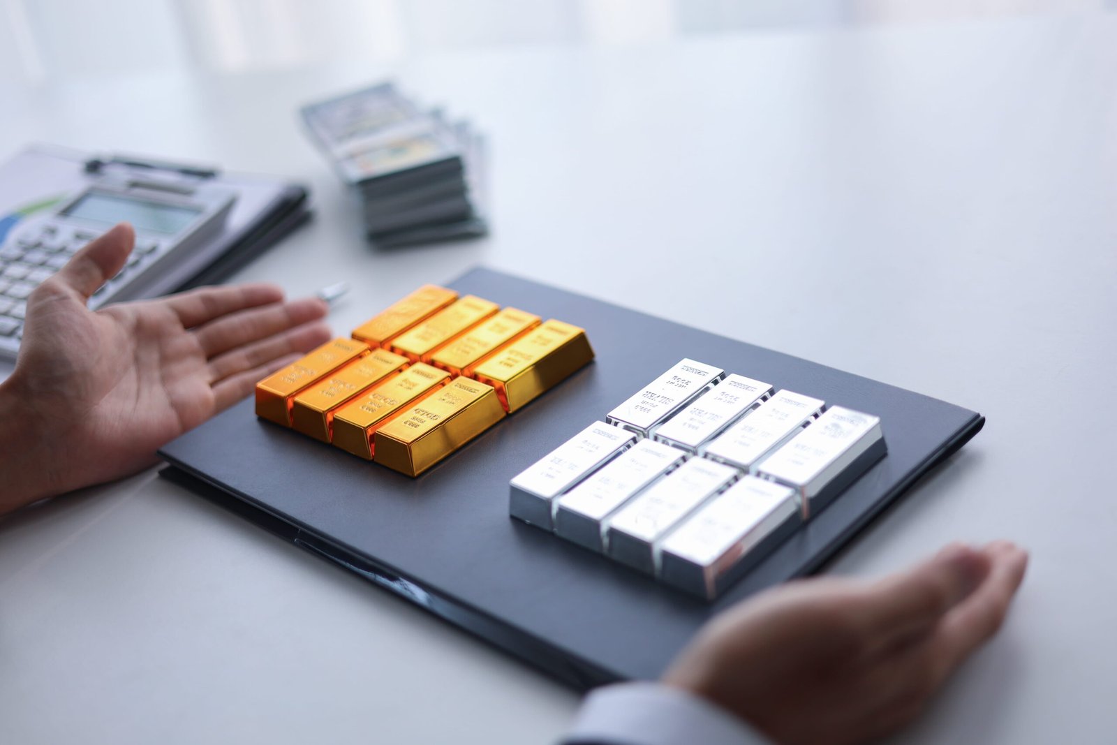 A side-by-side presentation of nine shiny gold bullion bars and nine polished silver bullion bars arranged on a black folder portfolio desk setting, serving as a clean visual guide for physical asset allocators comparing a Gold vs Silver Investment.